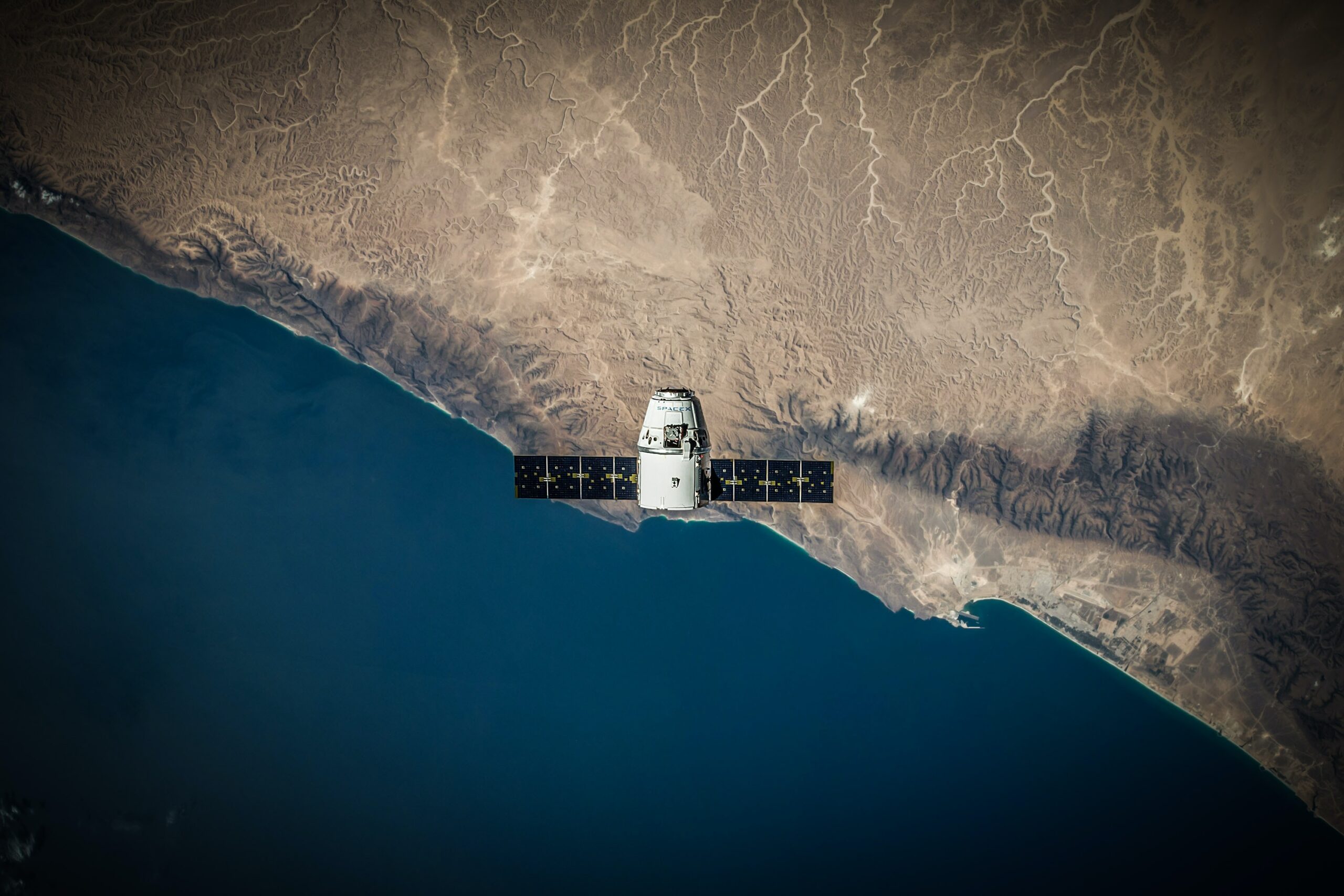 Space Satellite hovering above the coast; Source